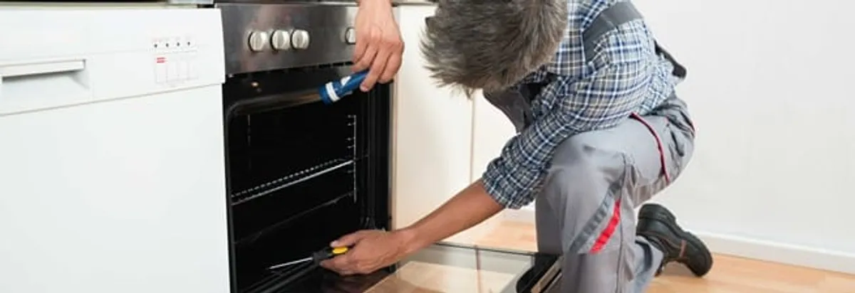Oven repair technician inspecting and servicing an electric oven in Lakewood, CO